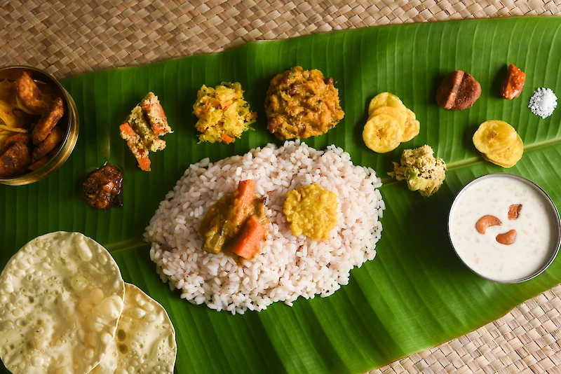 Perinteisesti Onam-ateria tarjoillaan banaaninlehdiltä. — Me käytämme keinotekoisia banaaninlehtiä, kertoo yrittäjä Biji Jayapradeep. (Kuvituskuva: Adobe Stock)