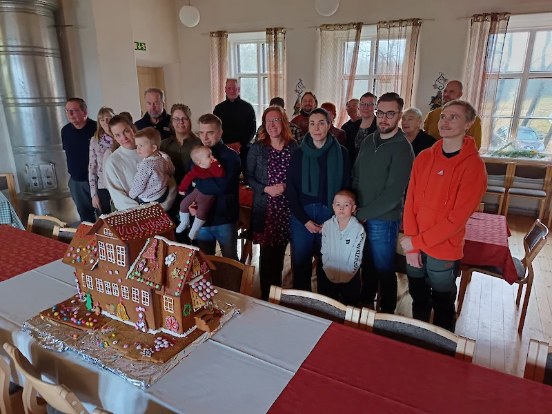 Vuolenkosken syyskokousväkeä, etualalla komea joulunavauksessa kyläläisten yhdessä koristelema kyläkoulu-piparkakkutalo. (Kuva: Merja Vainio)